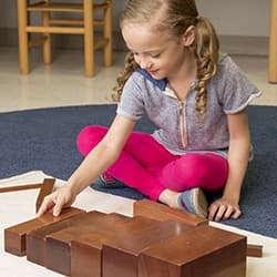 Girl playing with broad stair wooden blocks