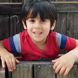 Boy outside on wooden fence