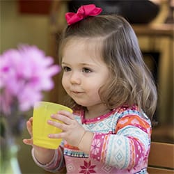 Niña pequeña con taza y flores