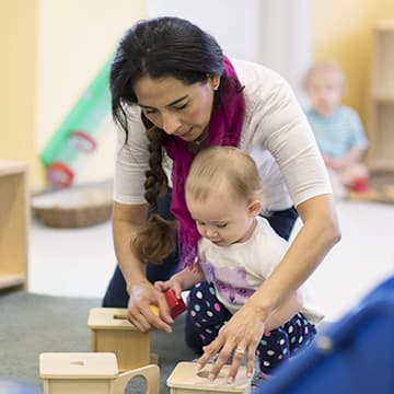 Infant and teacher play with blocks