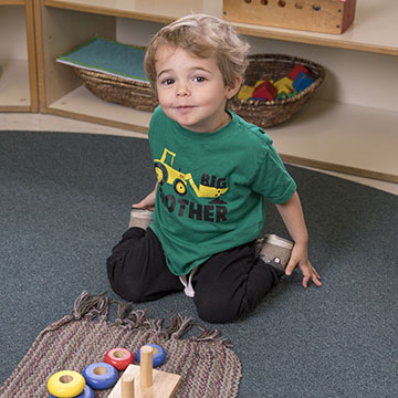 Niño pequeño arrodillado junto a sus juguetes